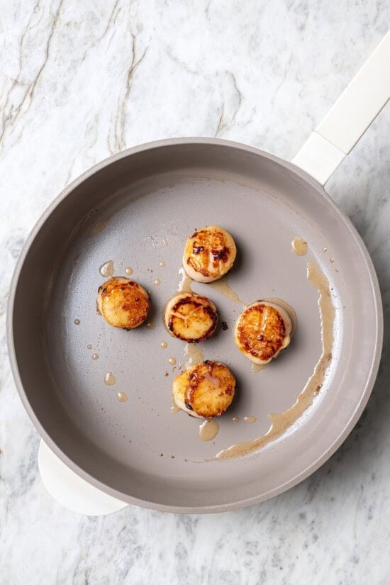 Overhead view of scallops searing in pan