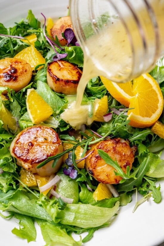 Pouring mojo vinaigrette onto scallop salad