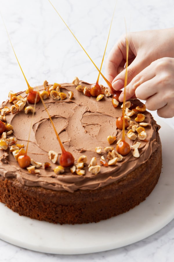 Placing candied hazelnut spikes on top of cake for decoration.