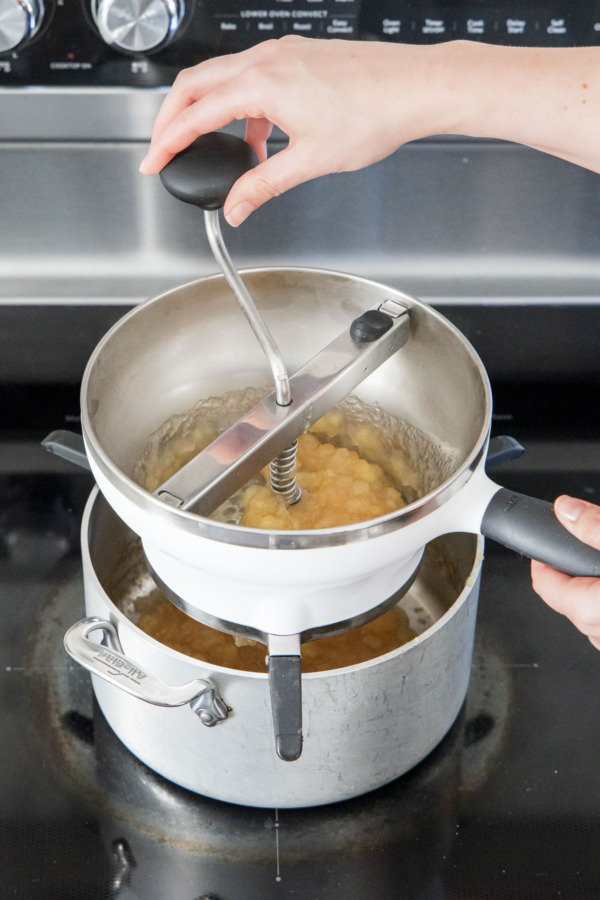 Running applesauce through the food mill for a smoother texture.