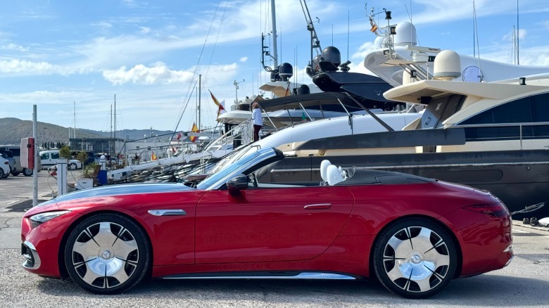 side view of a red Maybach SL with the top down in front of yachts