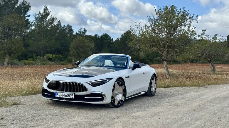 front three quarters of a white Maybach SL parked on dirt in front of trees