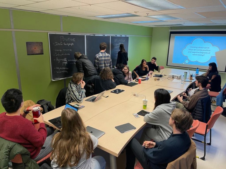 students taking part in a SandClub session gathered around a table in a seminar room