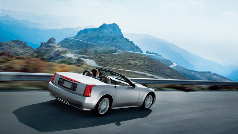 rear view of a silver XLR driving on a mountain road with its top down