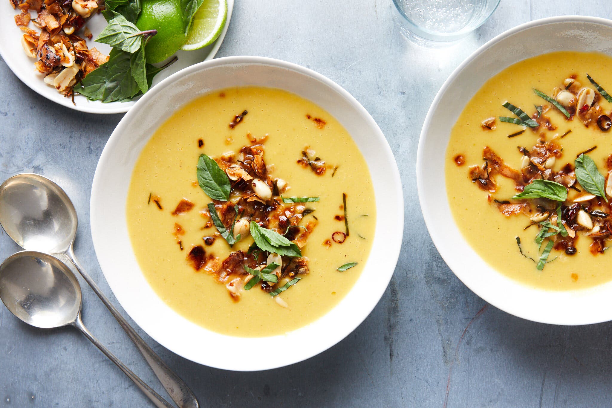 Two bowls of butternut squash soup are topped with a mix of coconut and chiles.