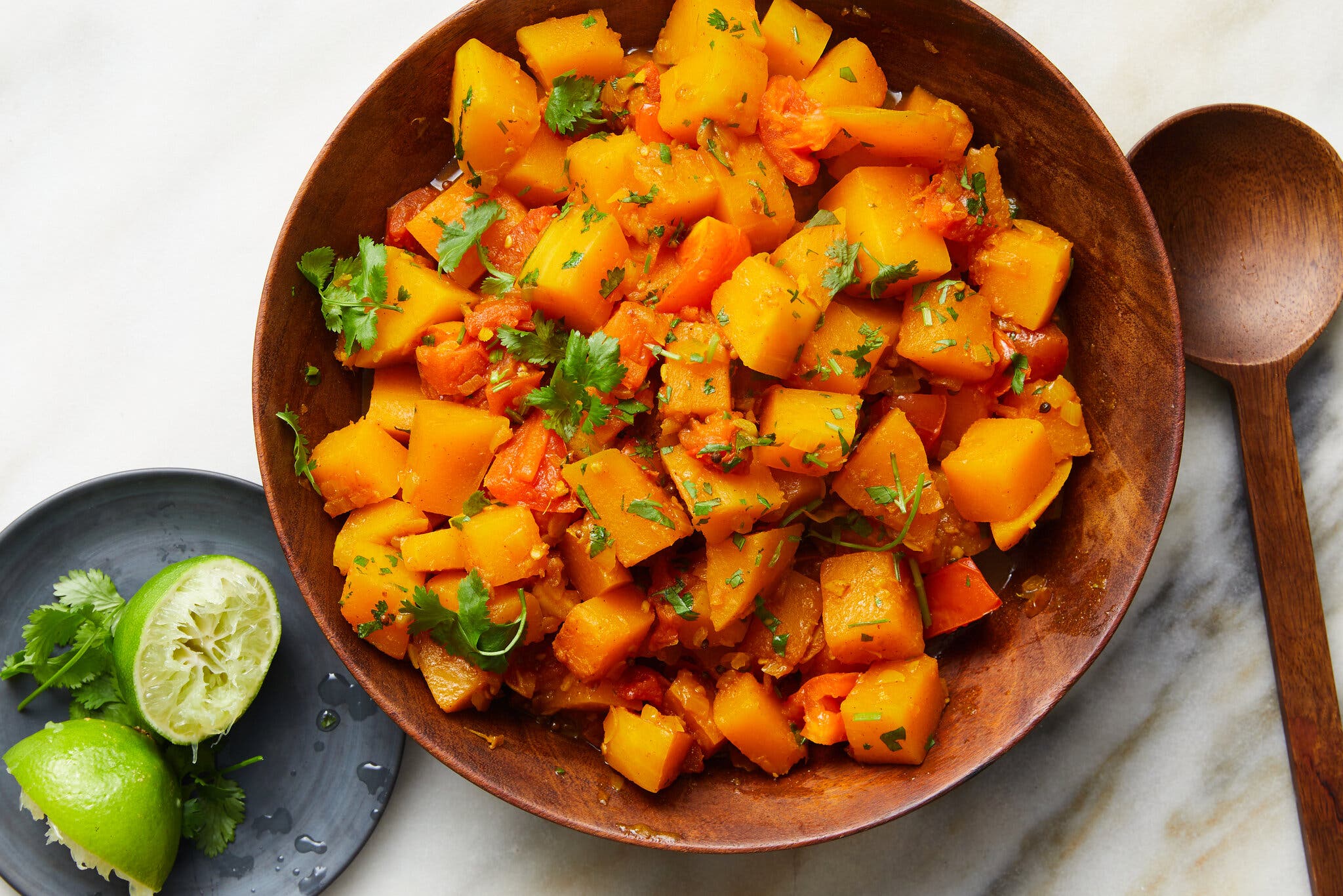 An overhead image of a wooden bowl filled with cubed butternut squash.