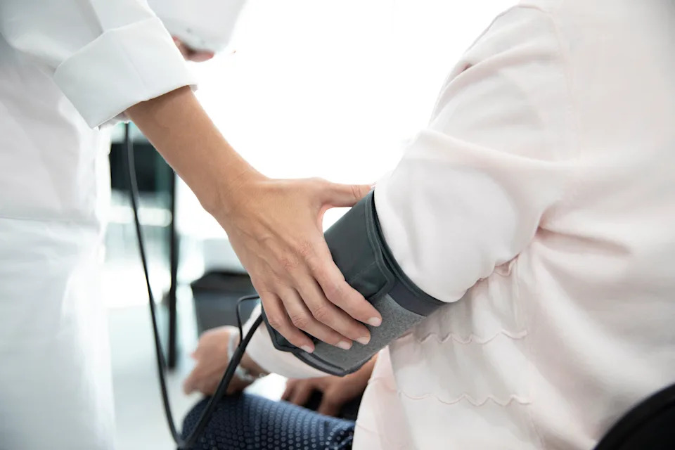 A healthcare professional measures a patient's blood pressure using a cuff, emphasizing the importance of routine health check-ups