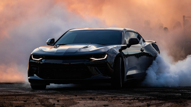 Black sports car burning rubber on back tires
