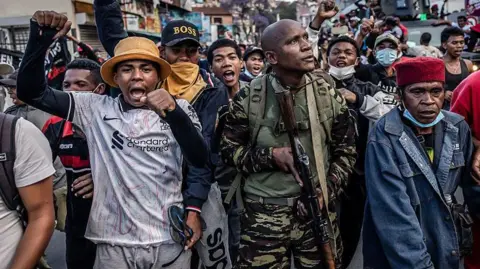 AFP via Getty Images Members of a Madagascar army contingent gather with protesters as protesters celebrate as they address them from Antananarivo's City Hall on October 11, 2025