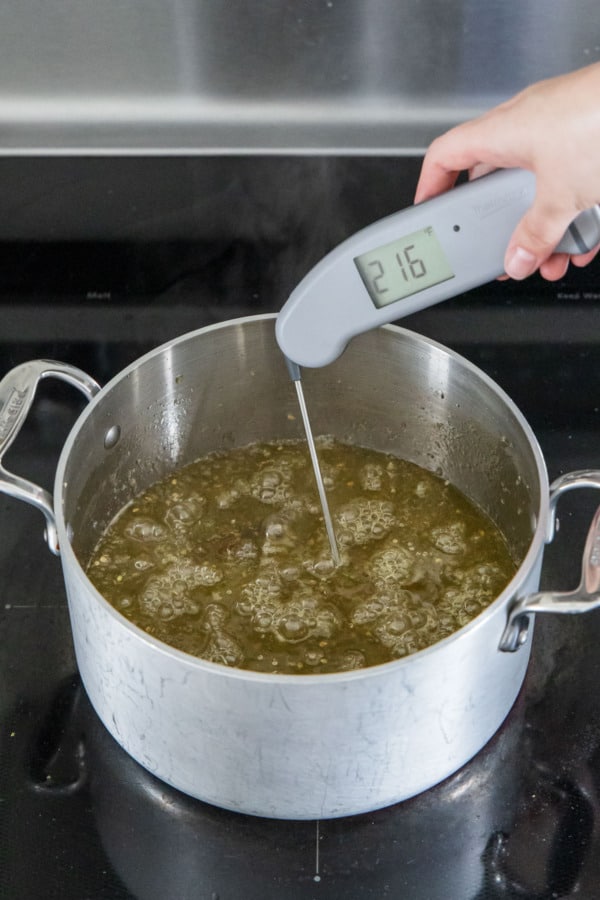 Measuring the temperature of the green tomato jam after cooking for approximately 35-45 minutes.