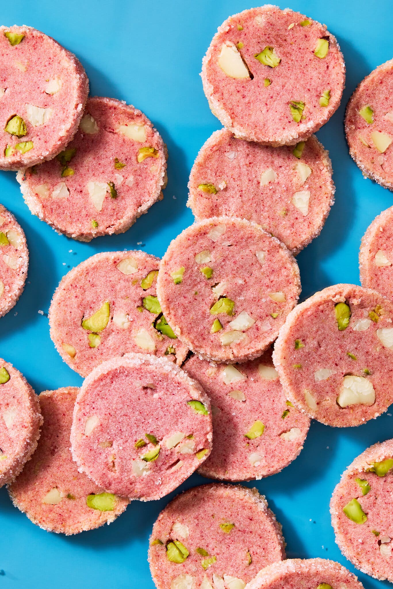 An overhead image of sliced pink cookies dotted with nuts.