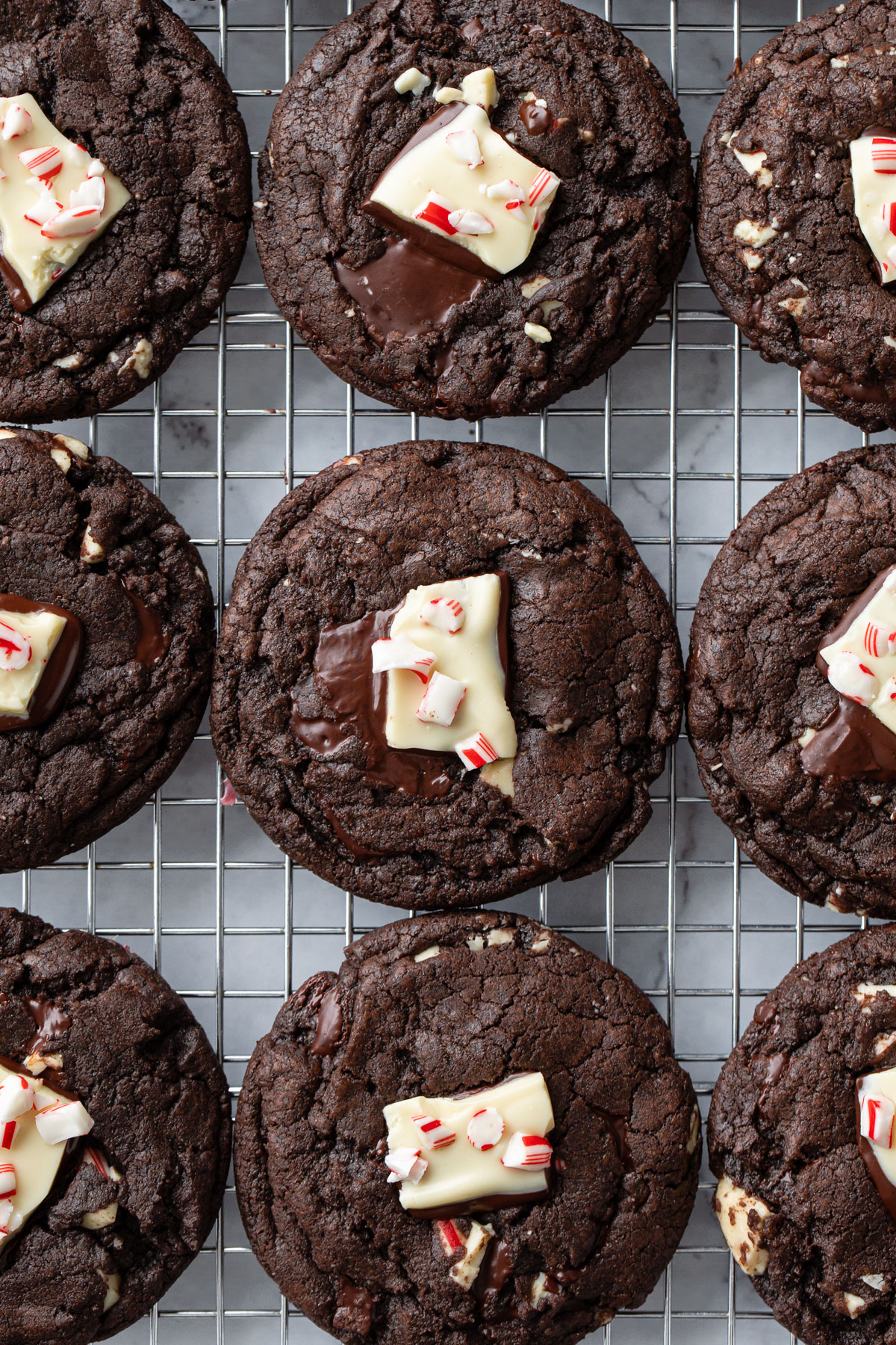 Overhead view, neat rows of Chocolate Peppermint Bark Cookies on a wire rack, each topped with a chunk of peppermint bark.